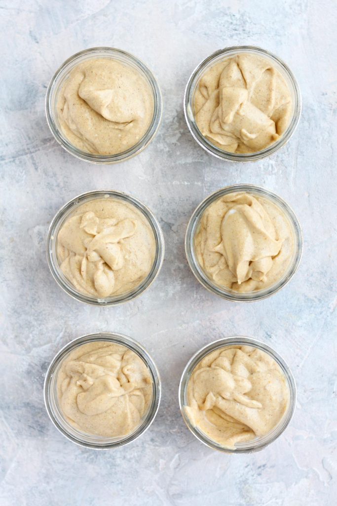 Pumpkin mousse layered on top of banana slices in six glass cups.