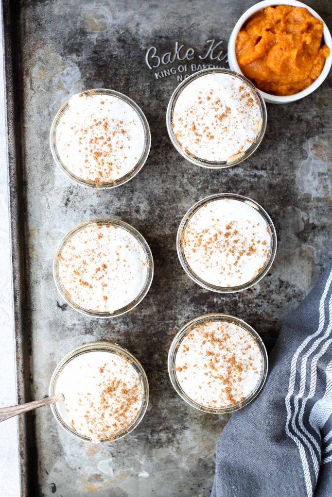 Pumpkin mousse cups on baking sheet with fresh whipped cream on top.