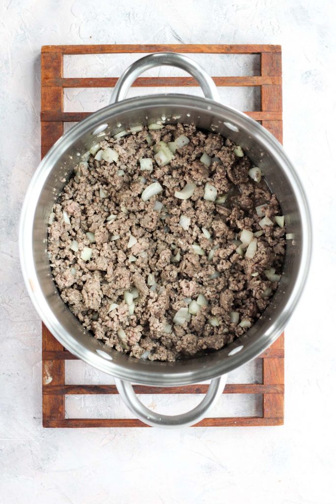 Ground beef and onions sautéing at the bottom of a soup pot.