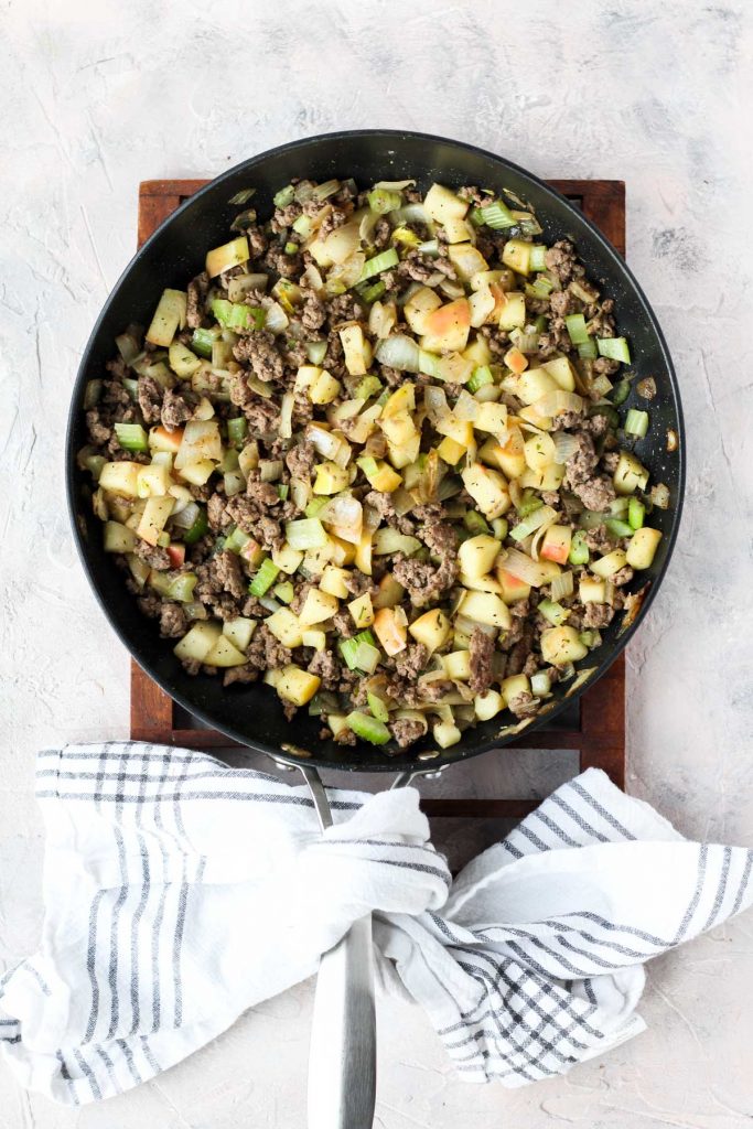 Meat, vegetables, and spices in saute pan.
