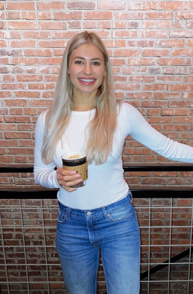 Girl with blonde hair holding coffee cup.