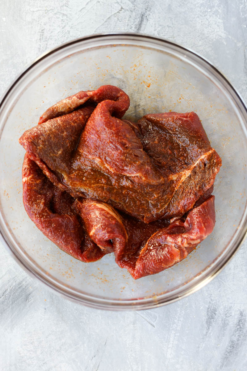 Steak marinating in a bowl.