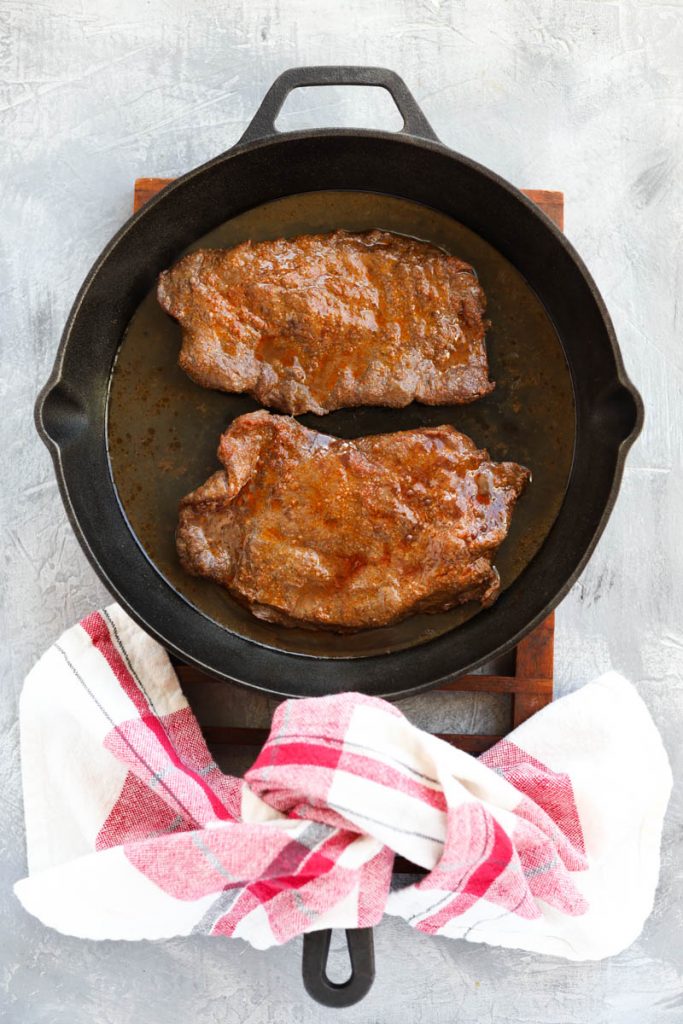 Cooked steak in cast iron skillet.