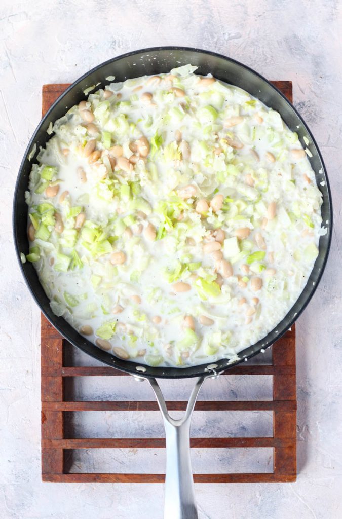 Onions, garlic, celery, beans, coconut milk, and seasoning in pan.