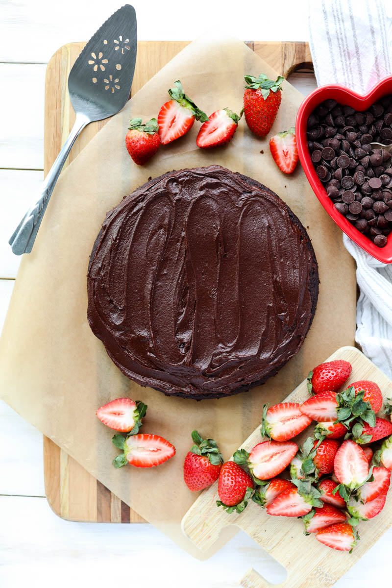 Chocolate cake on parchment apper with strawberries.