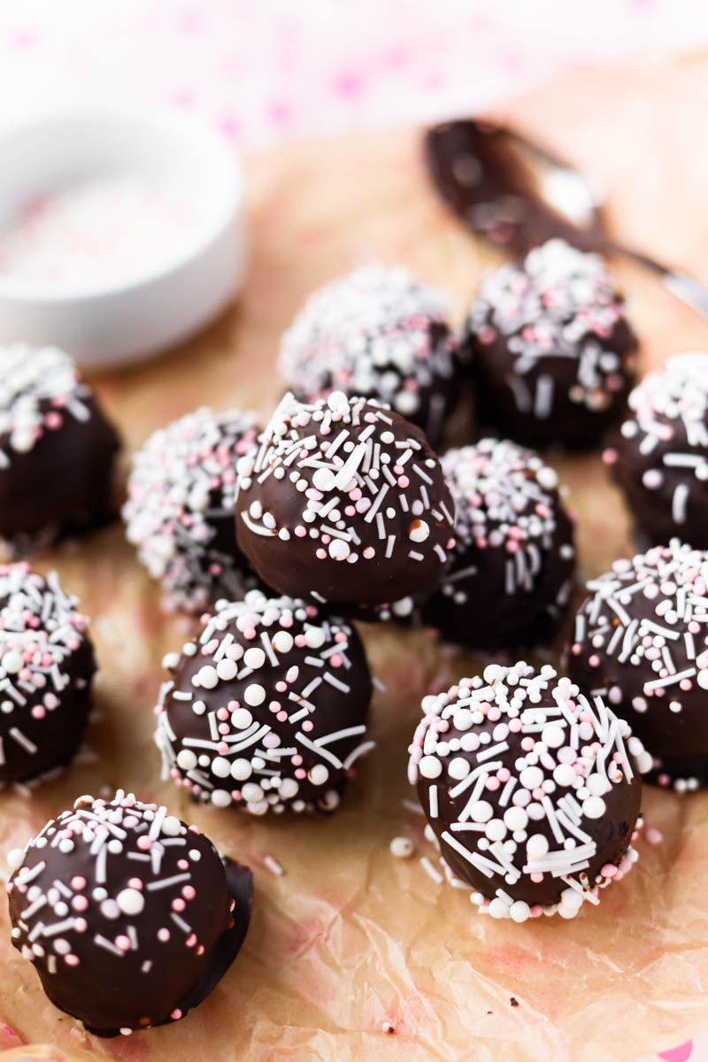 Chocolate cake pops with sprinkles on top.