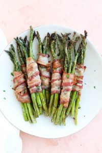 White plate with bacon wrapped asparagus.