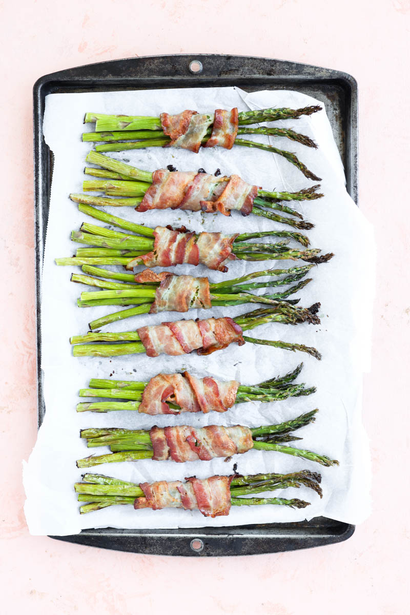 Bacon wrapped asparagus on baking sheet after coming out of the oven.