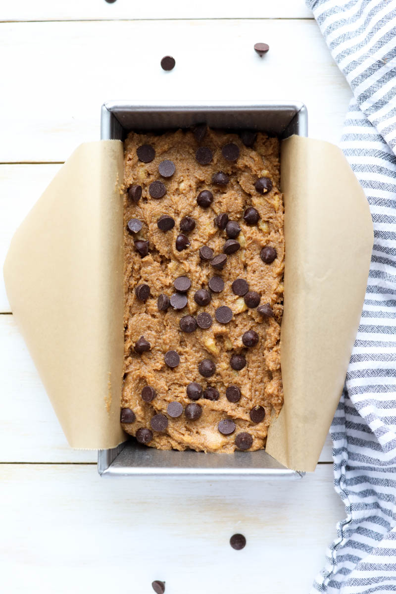 Banana bread dough with chocolate chips in a parchment paper lined bread pan.