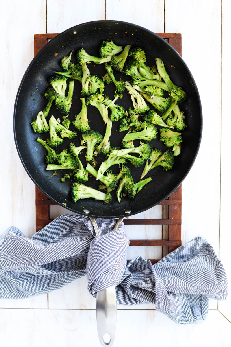 Broccoli florets cooking a skillet.