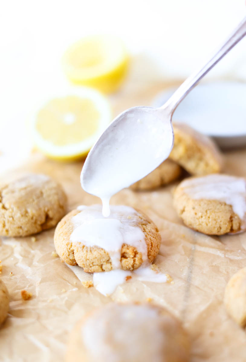 Spoon dripping lemon glaze onto cookie.