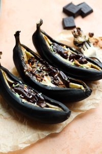 Air fried bananas on parchment paper with melted hoccolate and sprinkles.