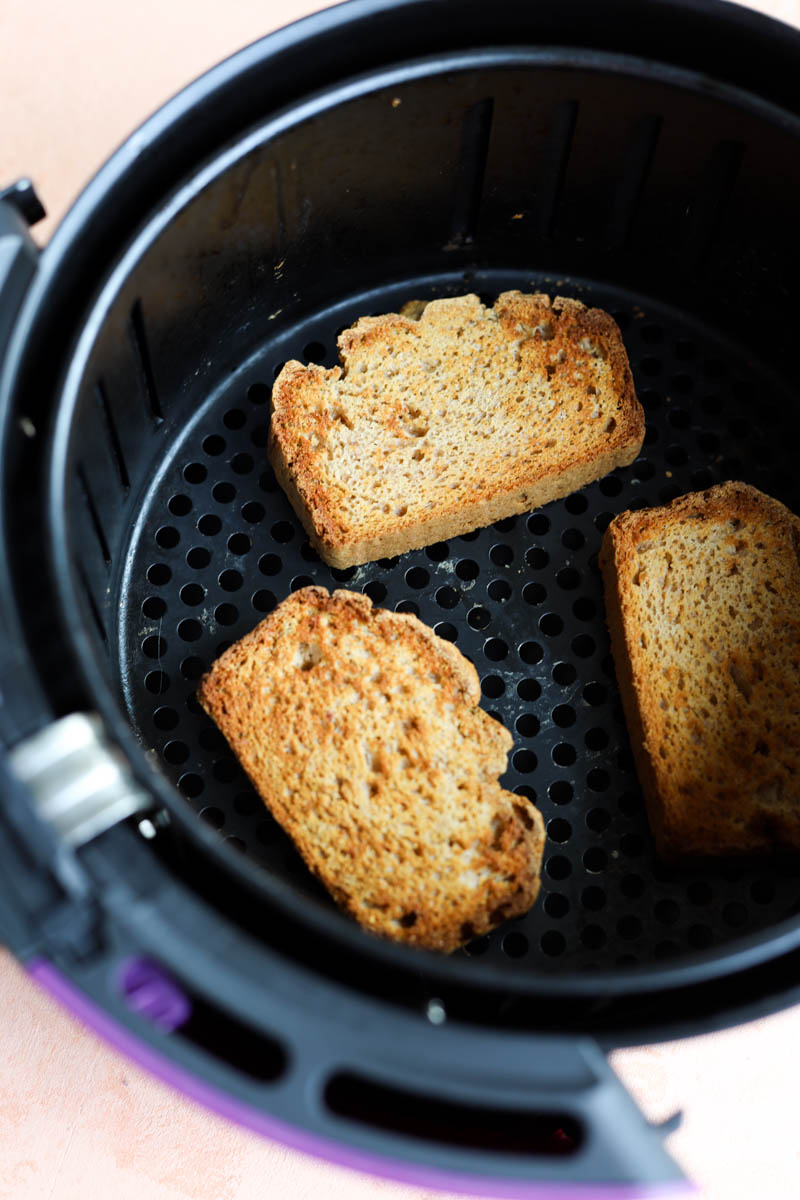 Golden brown toast slices in air fryer.