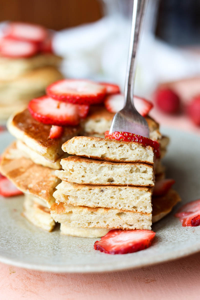 Fork stuck in big bite of banana pancakes.