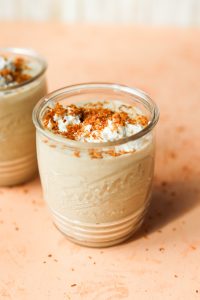 Glass jar with coconut milkshake with toasted coconut on top.