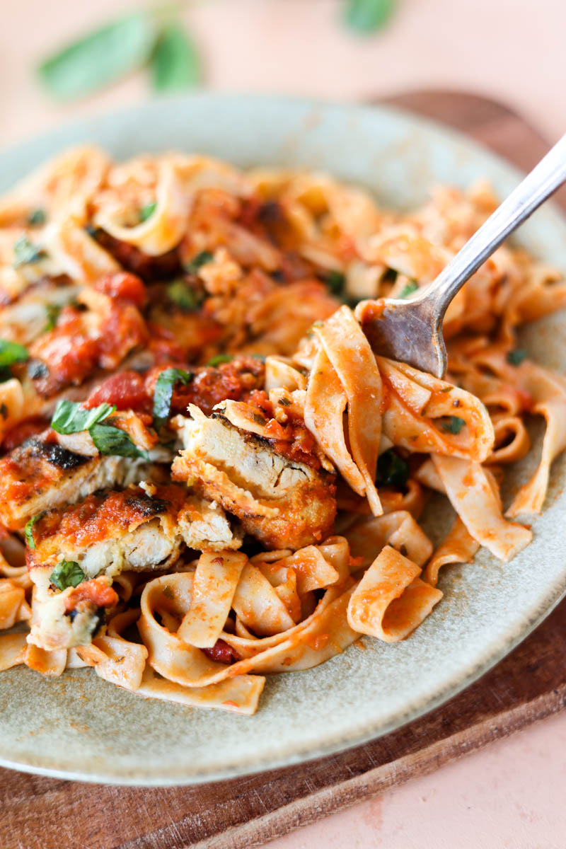 Fork with sauce and fettucine and chicken cutlets.