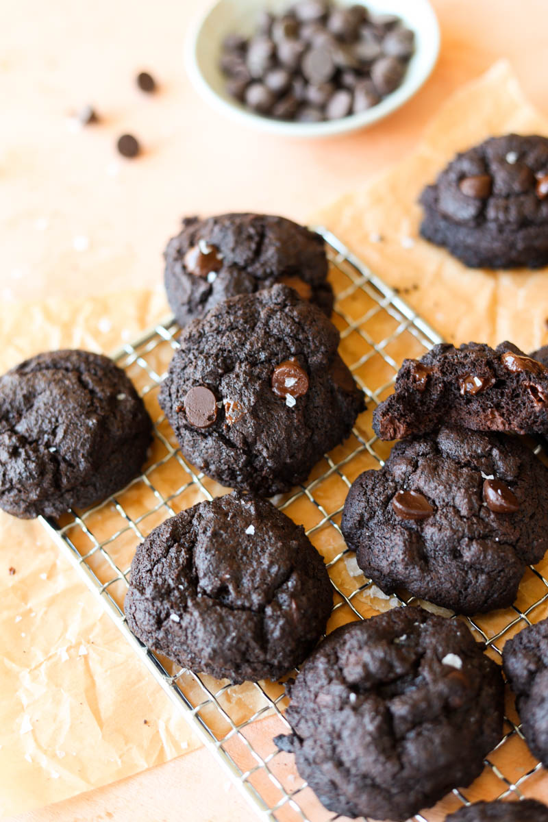 Chocolate cookies with chocolate chips on a metal rack.