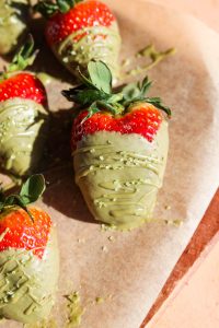 Close up of large chocolate covered strawberry with green sprinkles.