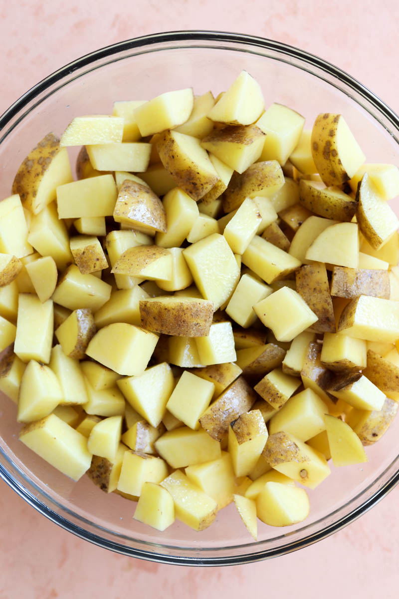 Cubed potatoes in a glass mixing bowl.