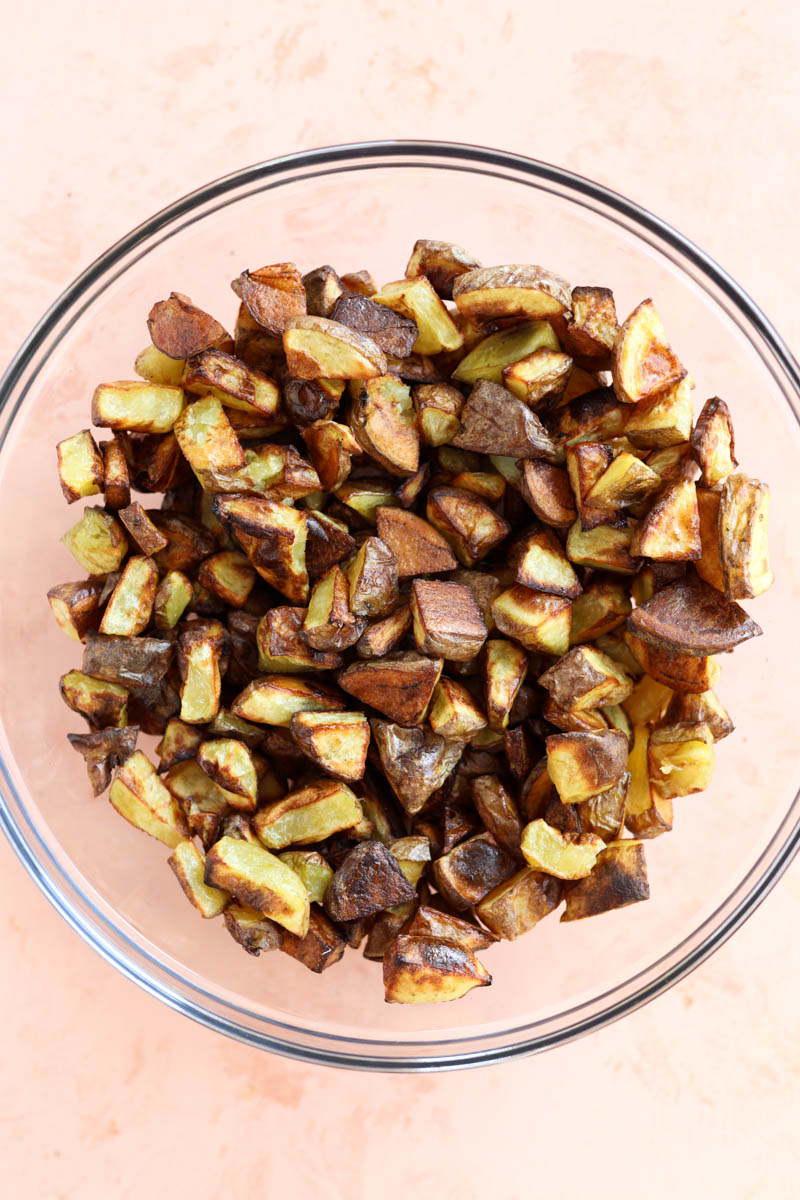 Roasted potatoes in a glass mixing bowl.