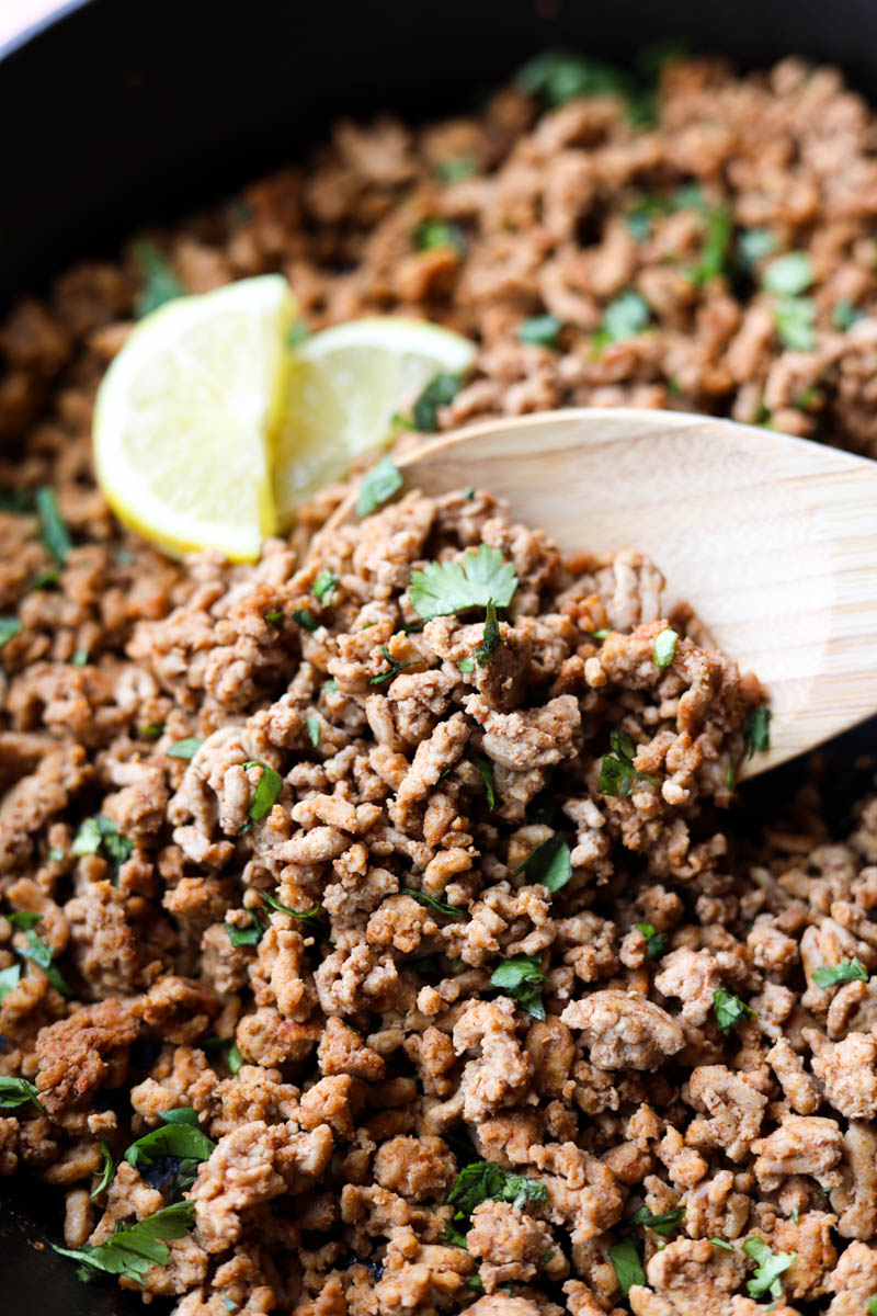 Wooden spoon scooping ground turkey.