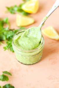 Spoon scooping out creamy avocado dressing.