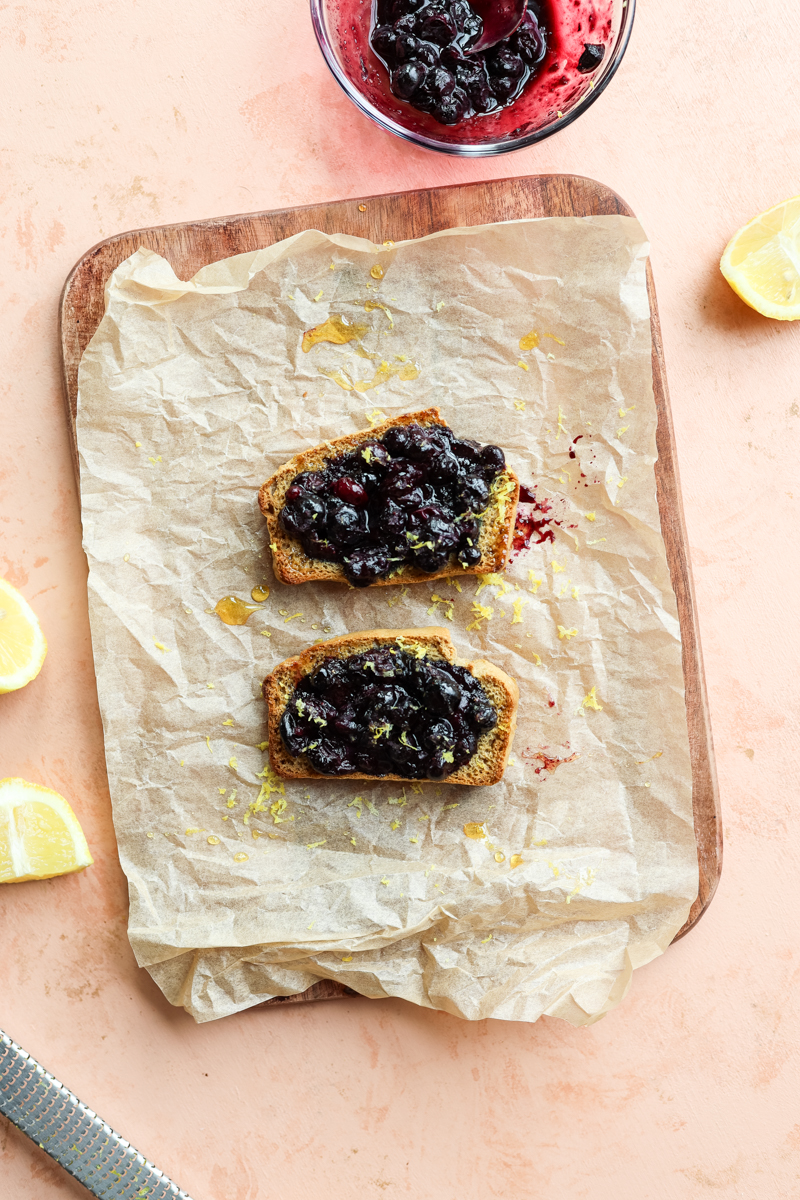 Blueberry toast on parchment paper with lemon slices and lemon zest.