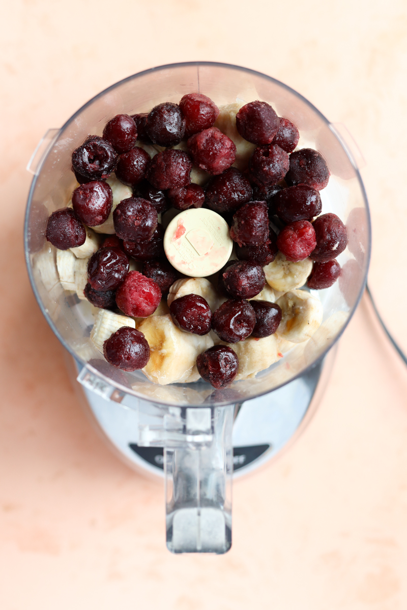 Frozen bananas, frozen cherries, vanilla extract, and coconut milk in a food processor.