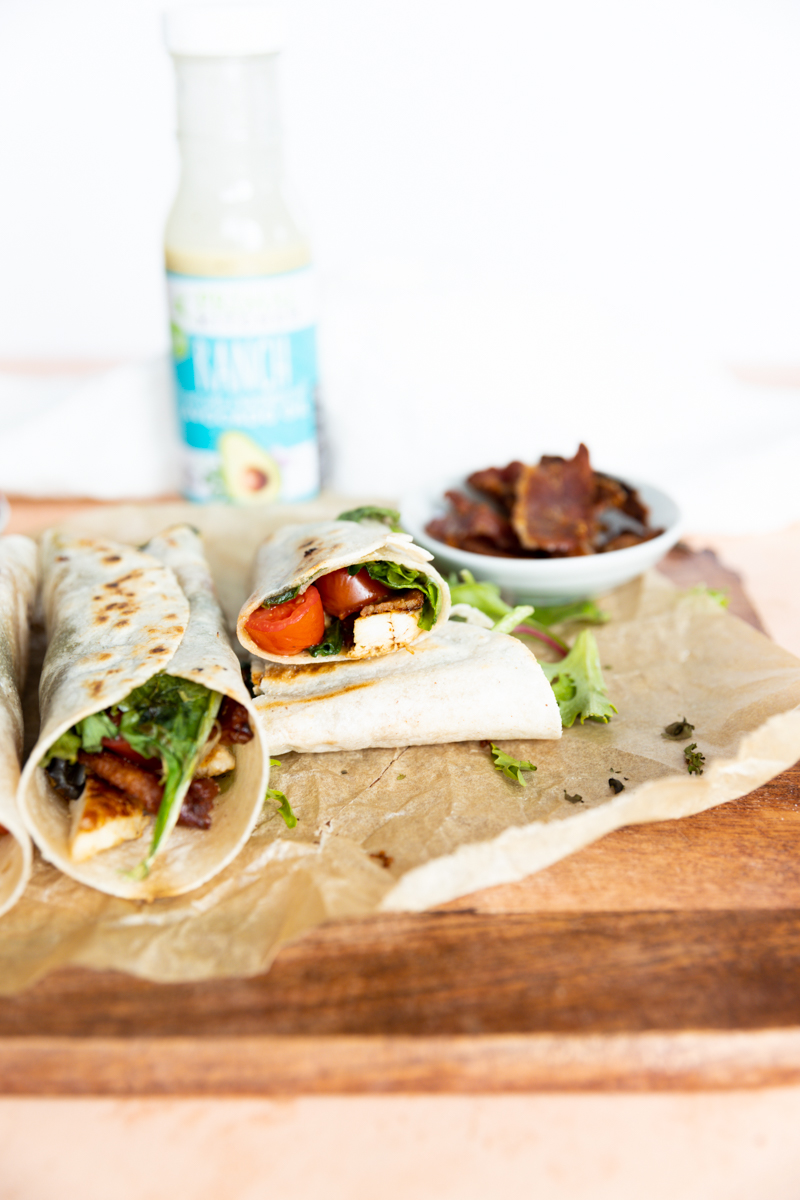 Chicken bacon ranch wraps on a wooden board with parchment paper.