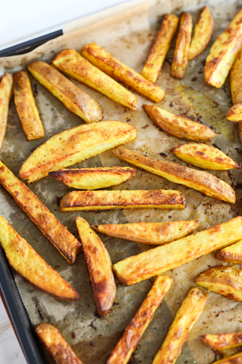 Baked French fries on a parhcment paper lined baking sheet.