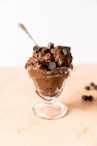 Brownie batter in a glass ice cream dish with a spoon.