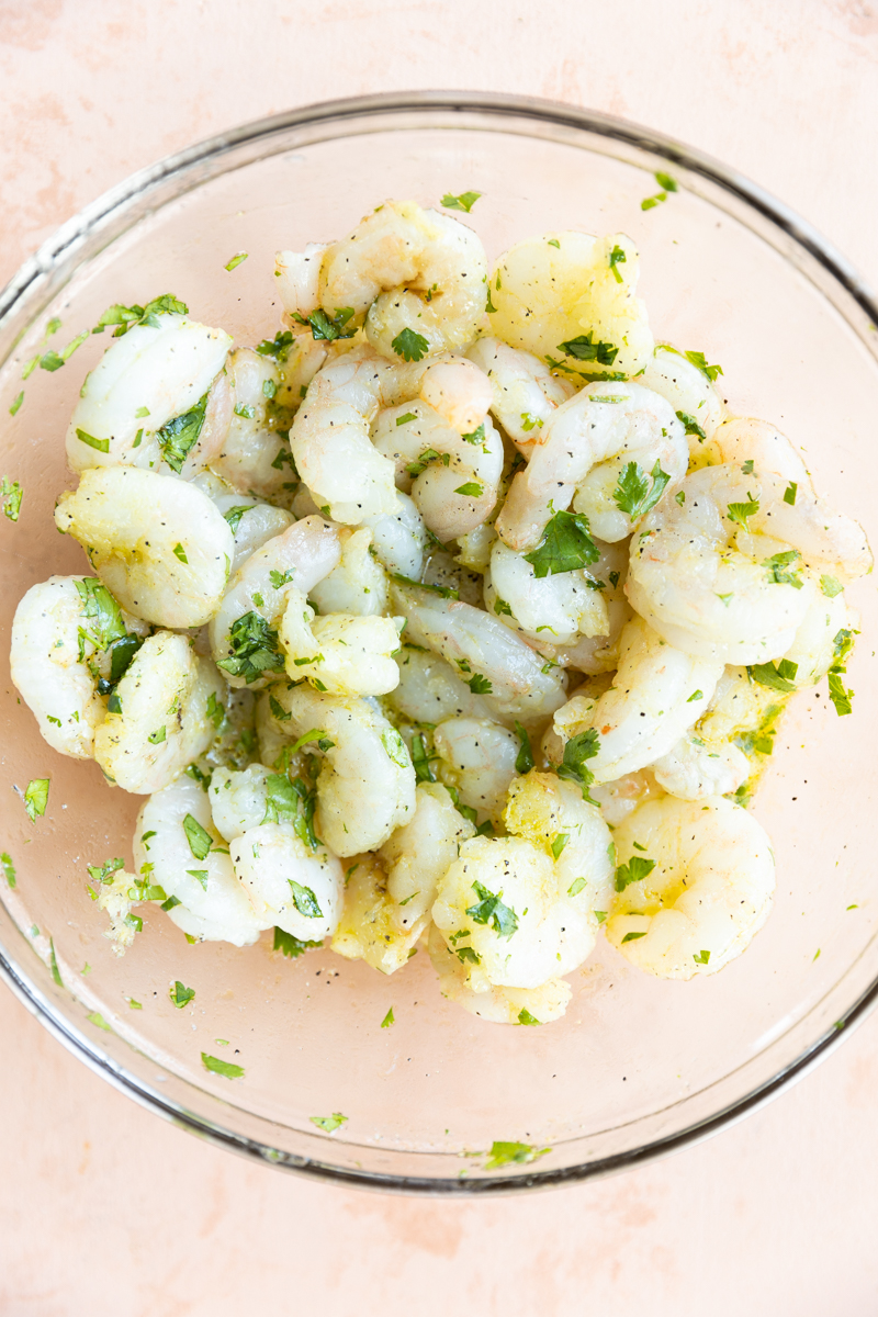 Shrimp marinating in a glass bowl.