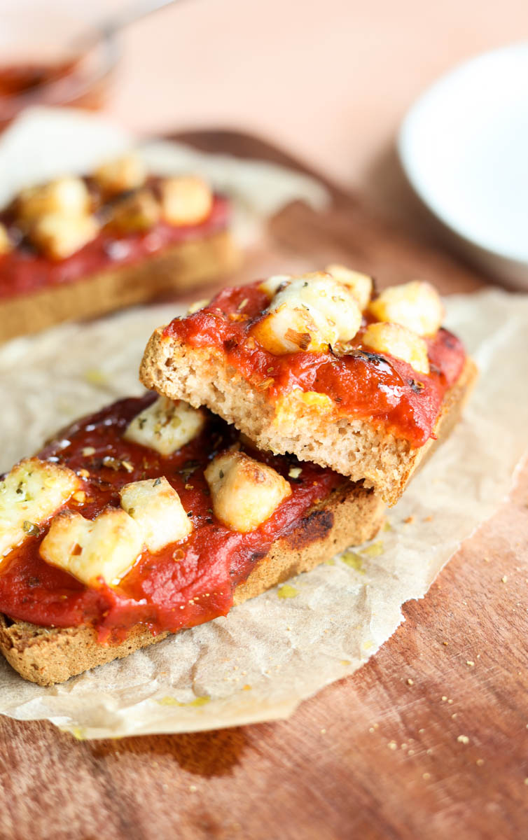 Pizza toast with bite taken out leaning on another piece of toast.