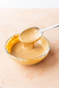 Spoon drizzling spicy burger sauce.