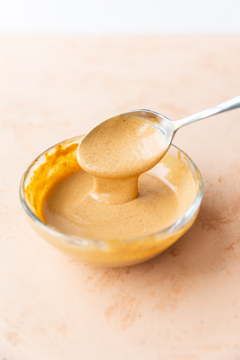 Spoon drizzling spicy burger sauce.