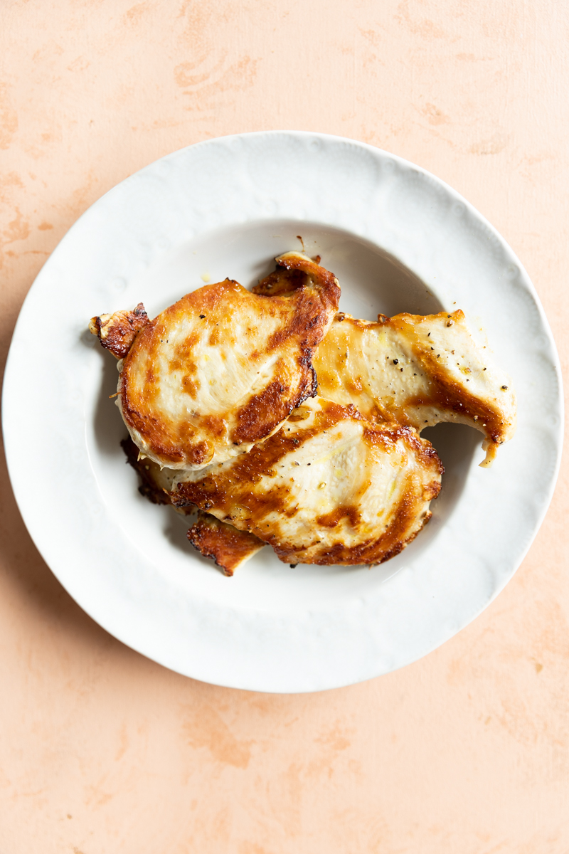 Cooked chicken breast on a white plate.