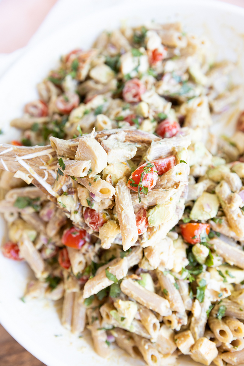 Wooden spoon holding up a scoop of pasta salad.