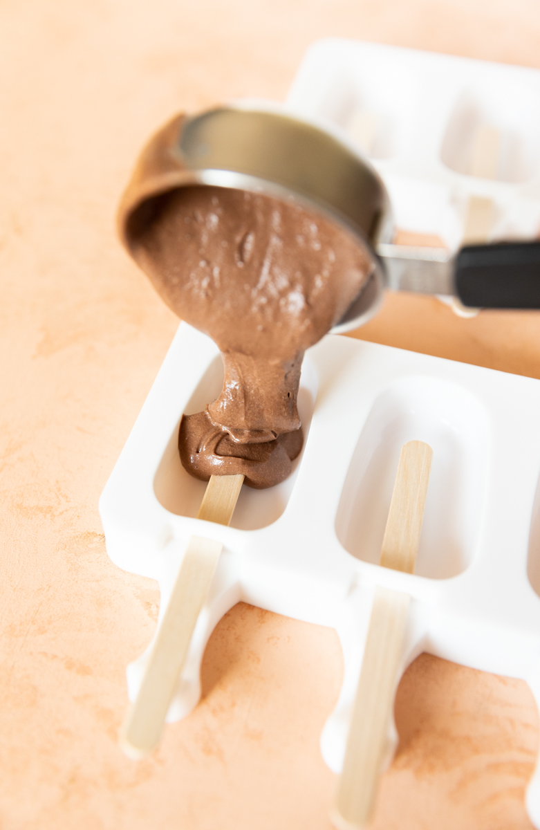 Pouring popsicle mixture into molds.