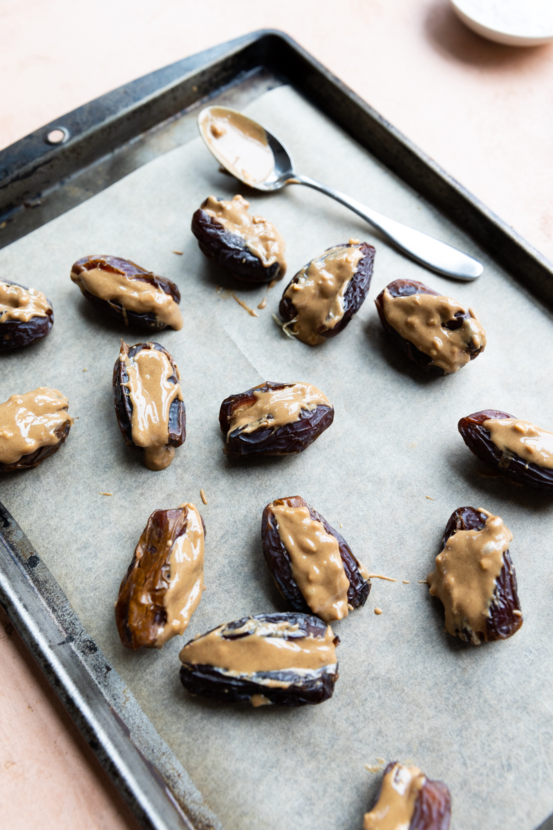 Dates stuffed with peanut butter on a parchment paper lined sheet.