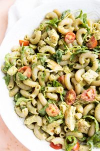 Pesto chicken pasta salad in a white serving bowl.