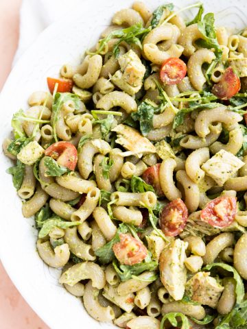 Pesto chicken pasta salad in a white serving bowl.