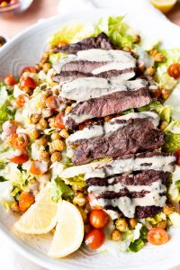 Steak Salad with caesar dressing drizzled on top.