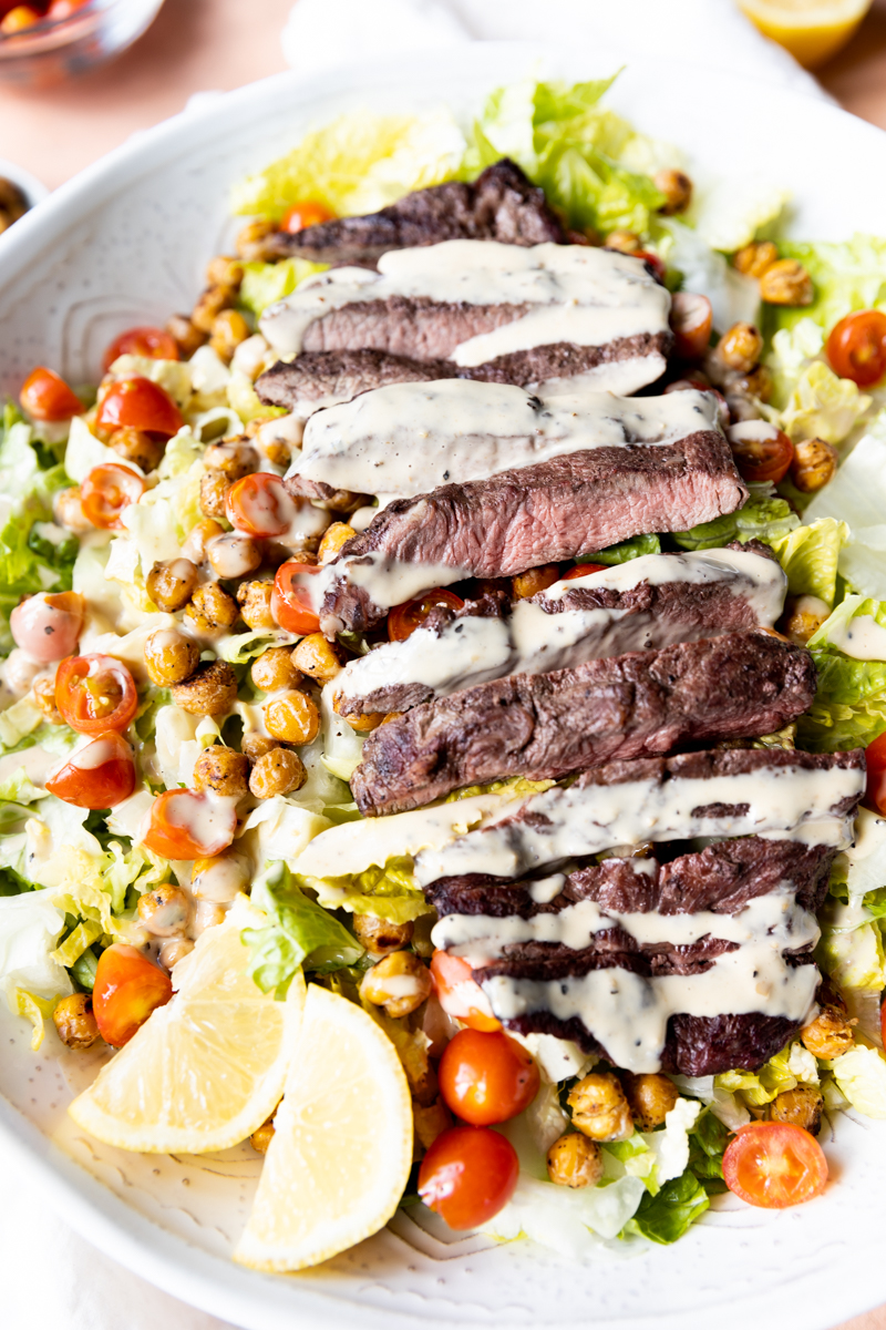 Steak Salad with caesar dressing drizzled on top.