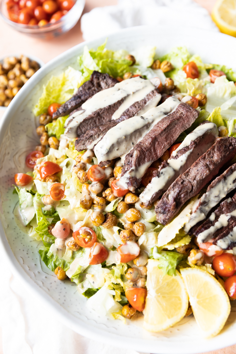 Steak caesar salad with dressing drizzled on top.
