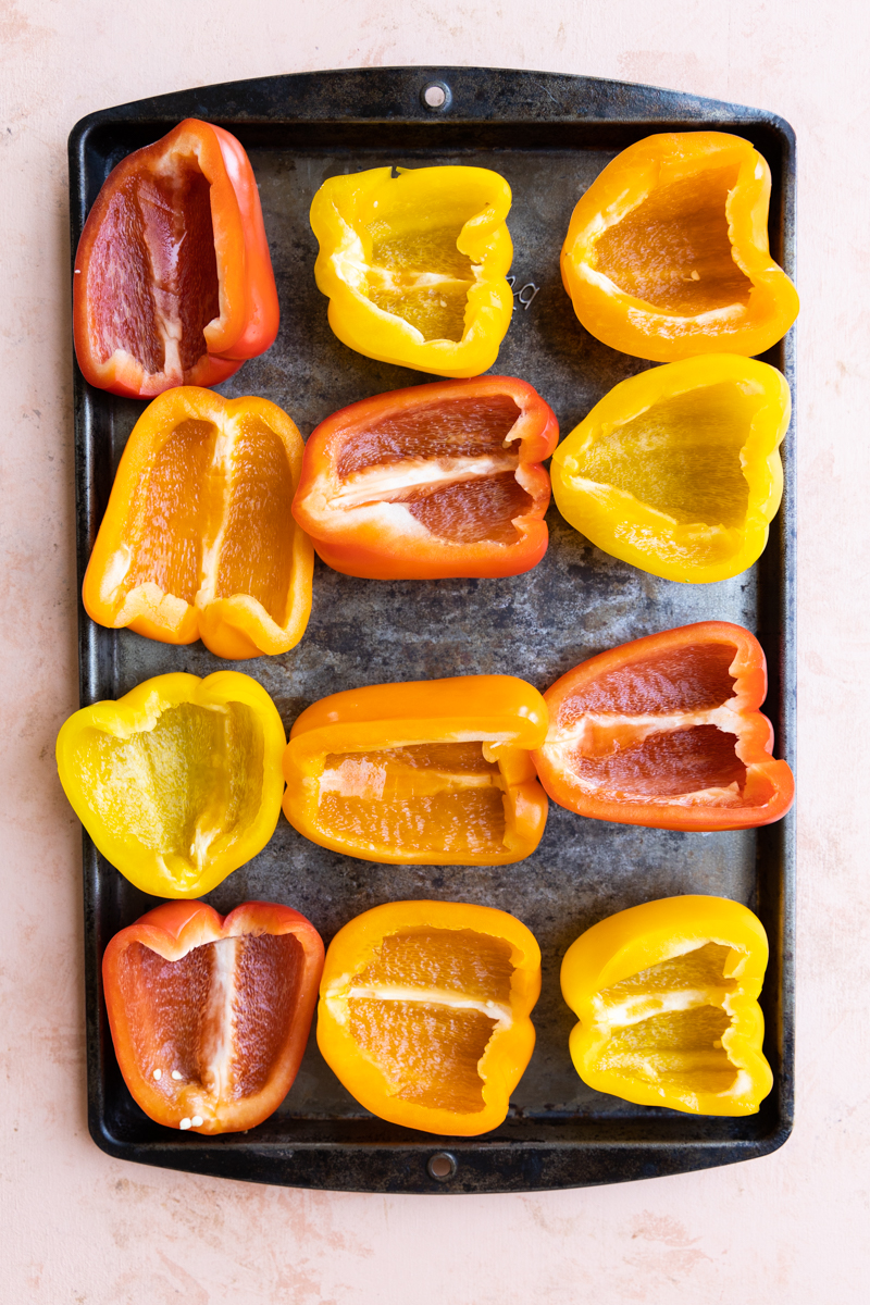 Peppers cut in half on a baking sheet.