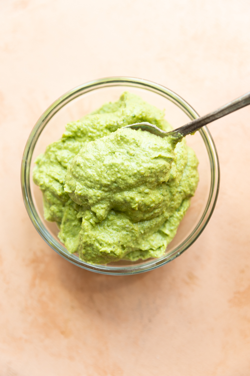 Pesto in a glass bowl with spoon.