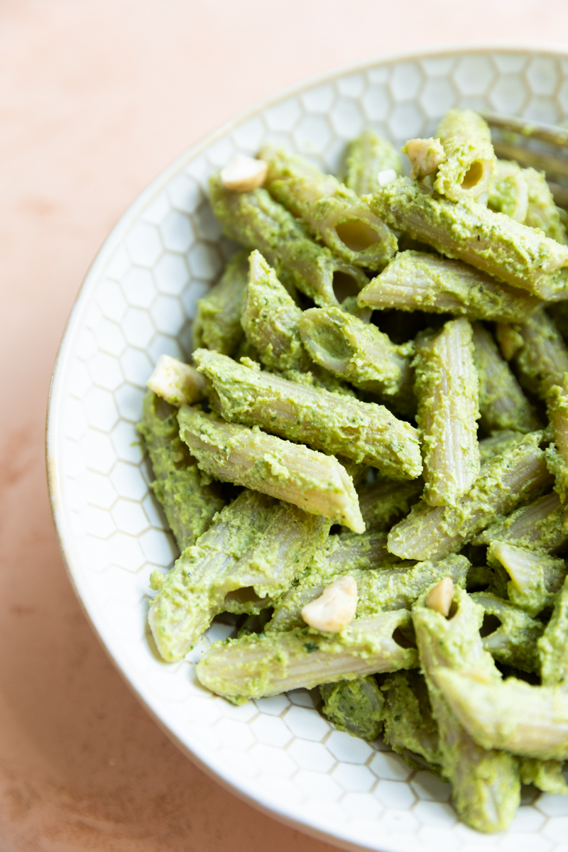 Pasta with pesto in a white bowl.