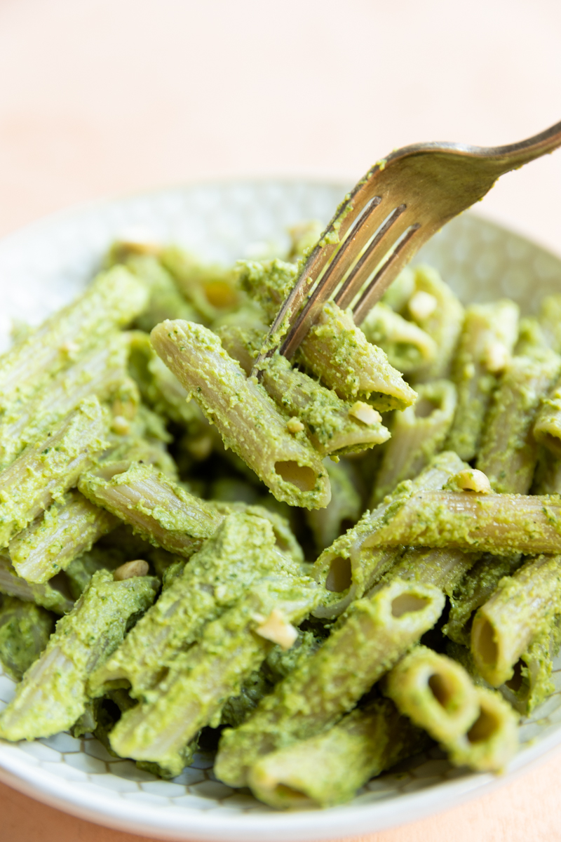 Fork with big bite of pesto on penne pasta.