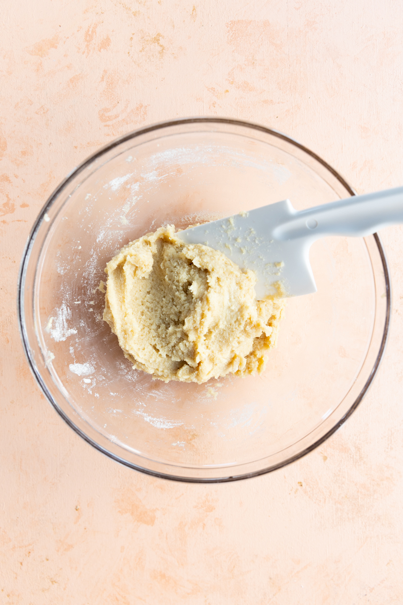 Cookie dough in a glass bowl with spatula.