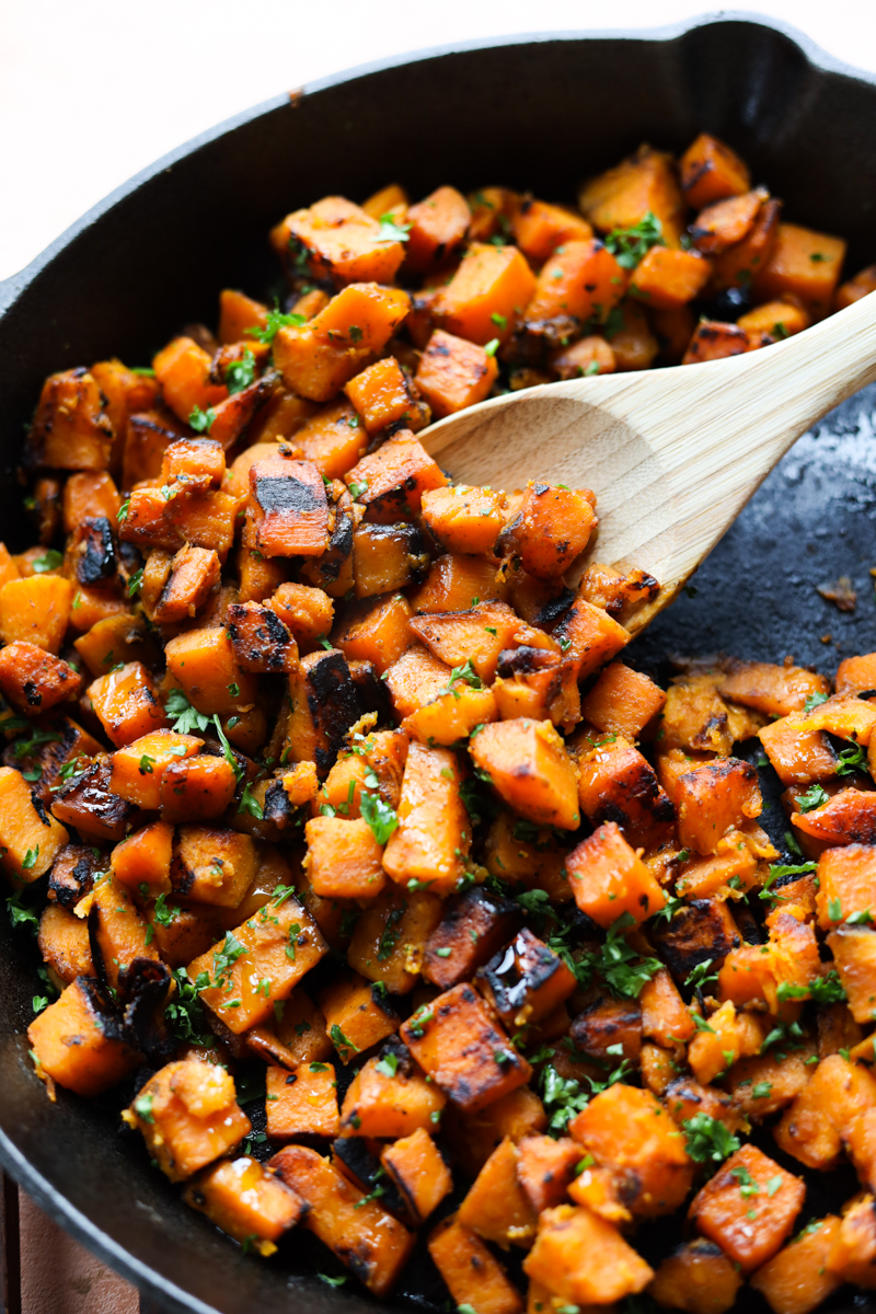 Wooden spoon scooping out sauteed sweet potato.